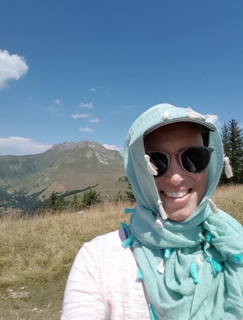 Angeline à la montagne, portant une casquette et une écharpe pour se protéger du soleil pendant la chimio après son annonce de cancer
