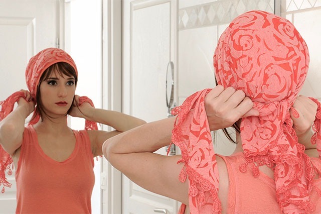 Femme devant un miroir mettant un turban pour retrouver estime de soi pendant un cancer