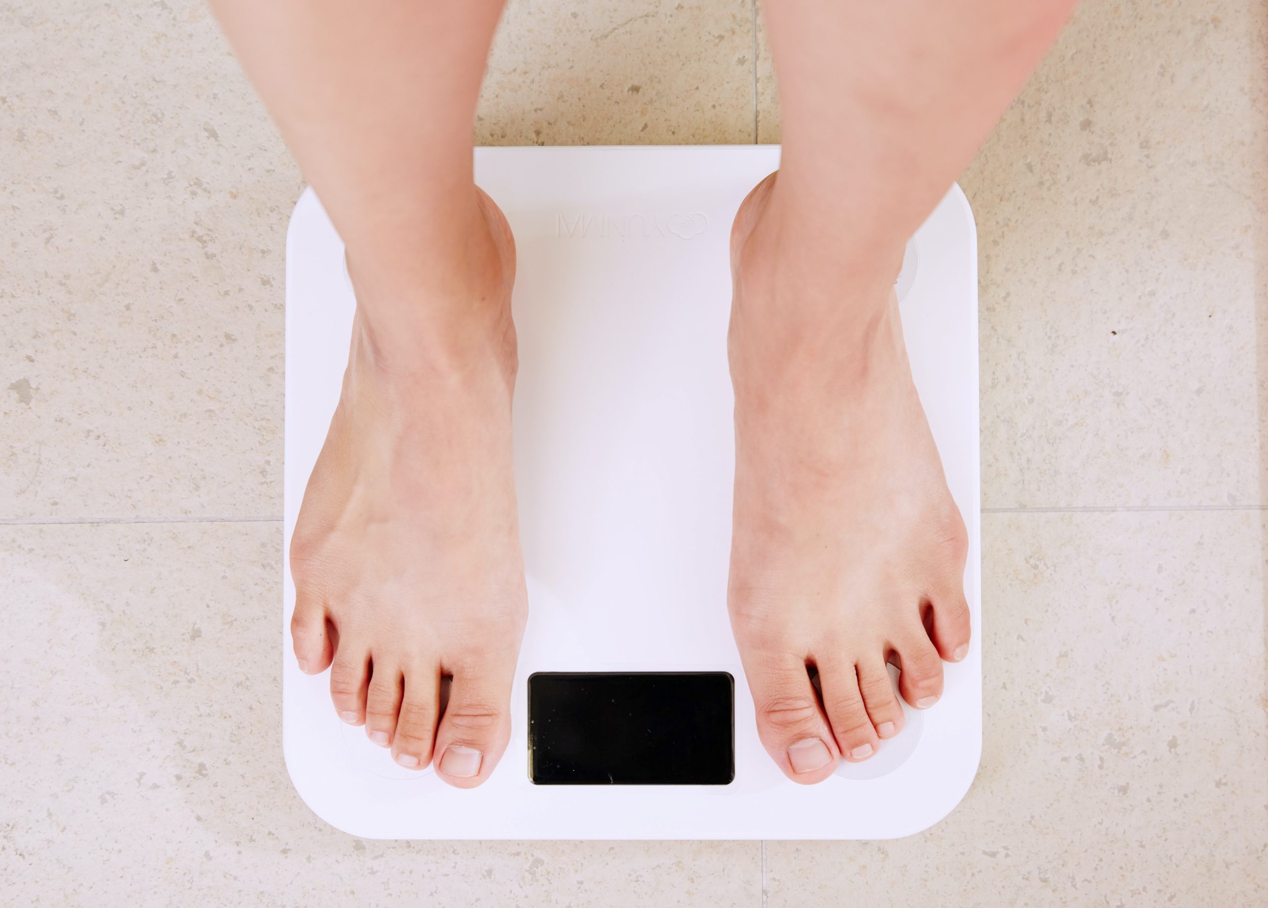 photo d'une personne sur une balance illustrant l'importance du contrôle du poids et donc de l'alimentation pendant un cancer
